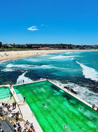 A coastal beach scene with a swimming pool and beachgoers.. Hotel Emerald