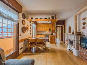Eine Küche mit Holzausstattung, einem Esstisch mit Stühlen, einem Kamin und einem Fernseher.