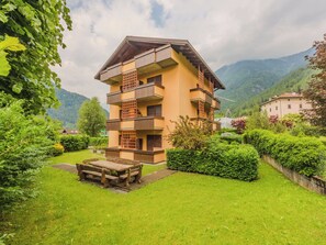 Ein mehrstöckiges Gebäude mit Balkonen, umgeben von üppiger Vegetation und Bergen.