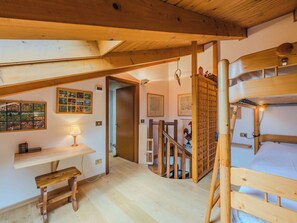 Ein Holzinnenraum mit einem Etagenbett, einem Schreibtisch und einer Treppe.