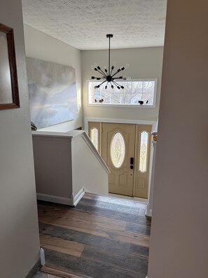 Una escalera conduce a una puerta con vidrieras, una lámpara en el techo y una pared con textura decorativa.