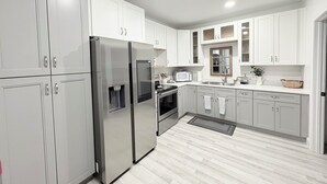 A modern kitchen with stainless steel appliances, white cabinetry, and a wooden floor. - East TN home with lake views & 2 kitchens (Morristown)