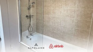 A bathroom with a glass shower enclosure, a bathtub, and beige tiled walls. - Stylish Stay in Emersons Green + WiFi + Garden (Emersons Green)