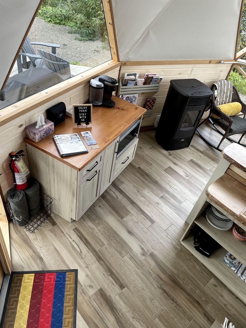 Une cuisine compacte avec des meubles de rangement en bois, un plan de travail, une cuisinière et un haut-parleur noir.
