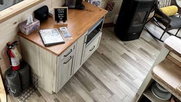 Une cuisine compacte avec des meubles de rangement en bois, un plan de travail, une cuisinière et un haut-parleur noir.
