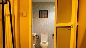 Ein Badezimmer mit Toilette, einem kleinen Fenster und einer Duschkabine.