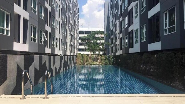 Ein modernes Gebäude mit Pool, großen Fenstern und Blick auf ein weiteres Gebäude im Hintergrund.