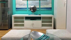 Eine moderne Küche mit integriertem Kühlschrank, Flachbildfernseher, einem weißen Schrank mit Glastüren und einem Glastisch mit Metallschüssel.