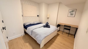 Un dormitorio con una cama, un escritorio y una silla.