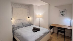 A bedroom with a bed, bedside lamps, a desk, and a chair.
