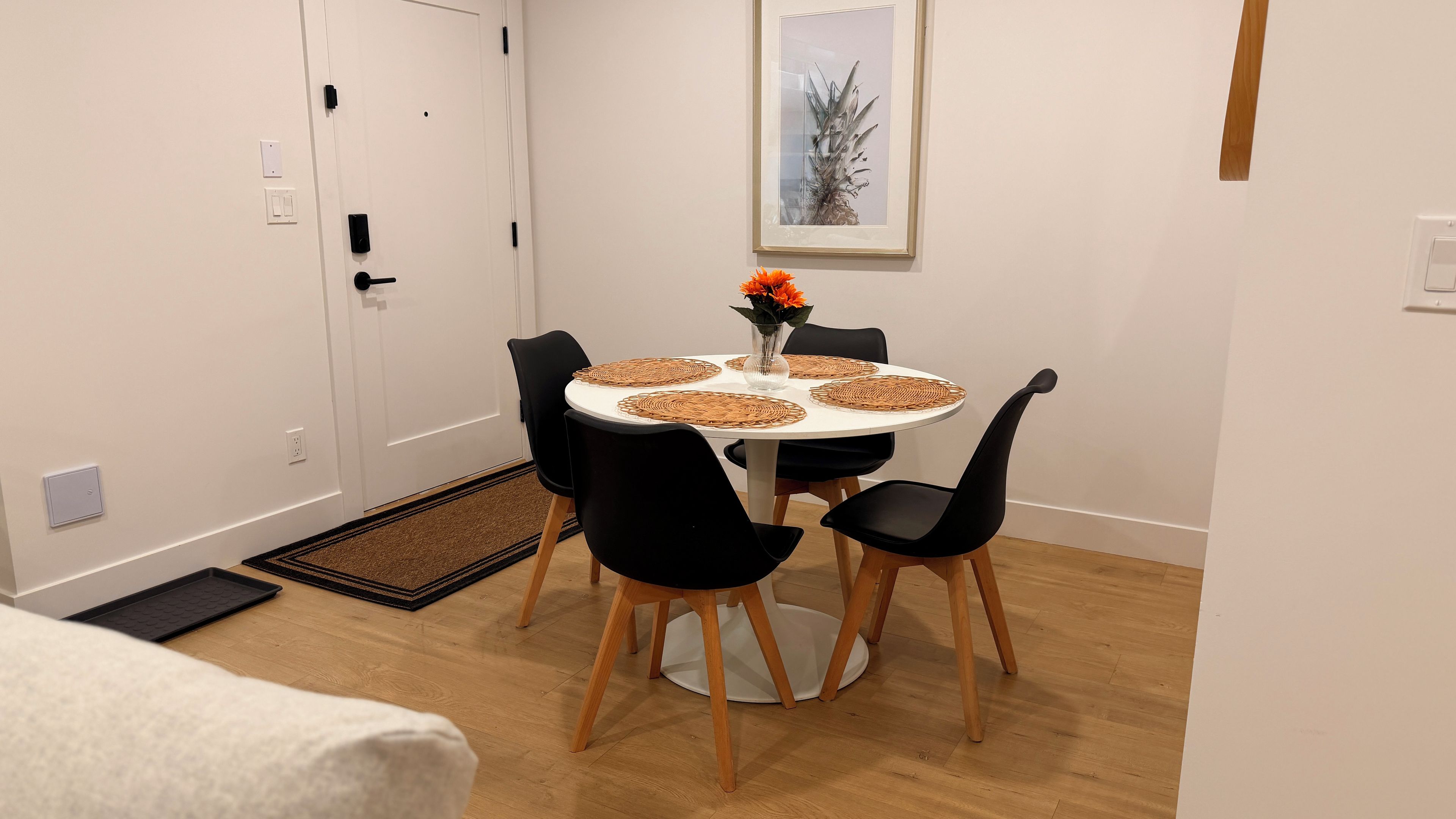 A dining area with a round table, black chairs, and a vase with flowers.