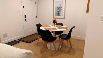 A dining area with a round table, black chairs, and a vase with flowers.