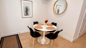 A dining area with a round table, black chairs, a vase with flowers, a framed picture on the wall, and a round mirror. - Modern Private Suite | Fast WiFi | Prime Location (Langley Township)