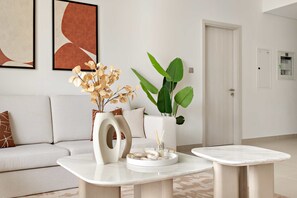 Een moderne woonkamer met een bank, een bijzettafeltje met decoratieve objecten en een potplant.