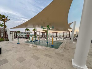 A rooftop pool area with exercise equipment, lounge chairs, and umbrellas. - Silkhaus Vacation Homes Prime 2BR in Yas Golf Collection (Abu Dhabi)