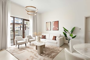 A modern living room with a sofa, armchairs, a coffee table, and a dining table. There are two framed artworks on the wall and a potted plant. - Silkhaus Vacation Homes Prime 2BR in Yas Golf Collection (Abu Dhabi)