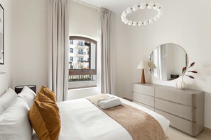 A hotel room with a bed, a dresser, a mirror, and a window with a view of buildings. - Silkhaus Vacation Homes Prime 2BR in Yas Golf Collection (Abu Dhabi)
