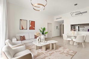 A modern living room with a sofa, coffee table, and dining area. - Silkhaus Vacation Homes Prime 2BR in Yas Golf Collection (Abu Dhabi)