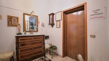 Quarto com penteadeira de madeira, espelho, relógio e porta com a inscrição 'SALONE DEL CERASUOLO'.
