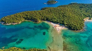An aerial view of a tropical island with clear turquoise waters, a sandy beach, and dense forested areas. - Esperides Estia - Sea View Syvota Stay w Balcony (Igoumenitsa)
