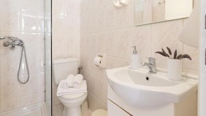 A bathroom with a shower, toilet, sink, and a mirror. - Esperides Estia - Sea View Syvota Stay w Balcony (Igoumenitsa)