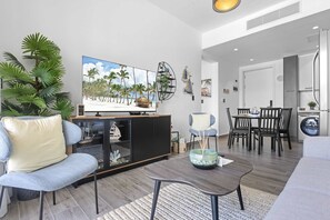 Ein modernes Wohnzimmer mit Fernseher, Sofa, Couchtisch und Essbereich.