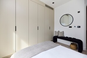 A bedroom with a bed, a black headboard, a round mirror, a wardrobe, and a bedside table with a basket. - Pembridge Residence Bright Stylish Notting Hill 17 (London)