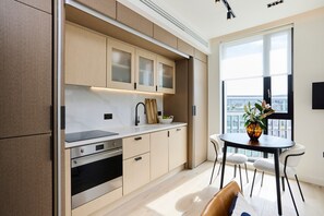 A modern kitchen with built-in appliances, a dining area with a table and chairs, and a large window offering a view. - Pembridge Residence Bright Stylish Notting Hill 17 (London)
