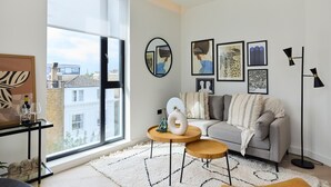 Uma sala de estar moderna com uma janela grande, um sofá, uma mesa de centro e obras de arte nas paredes.