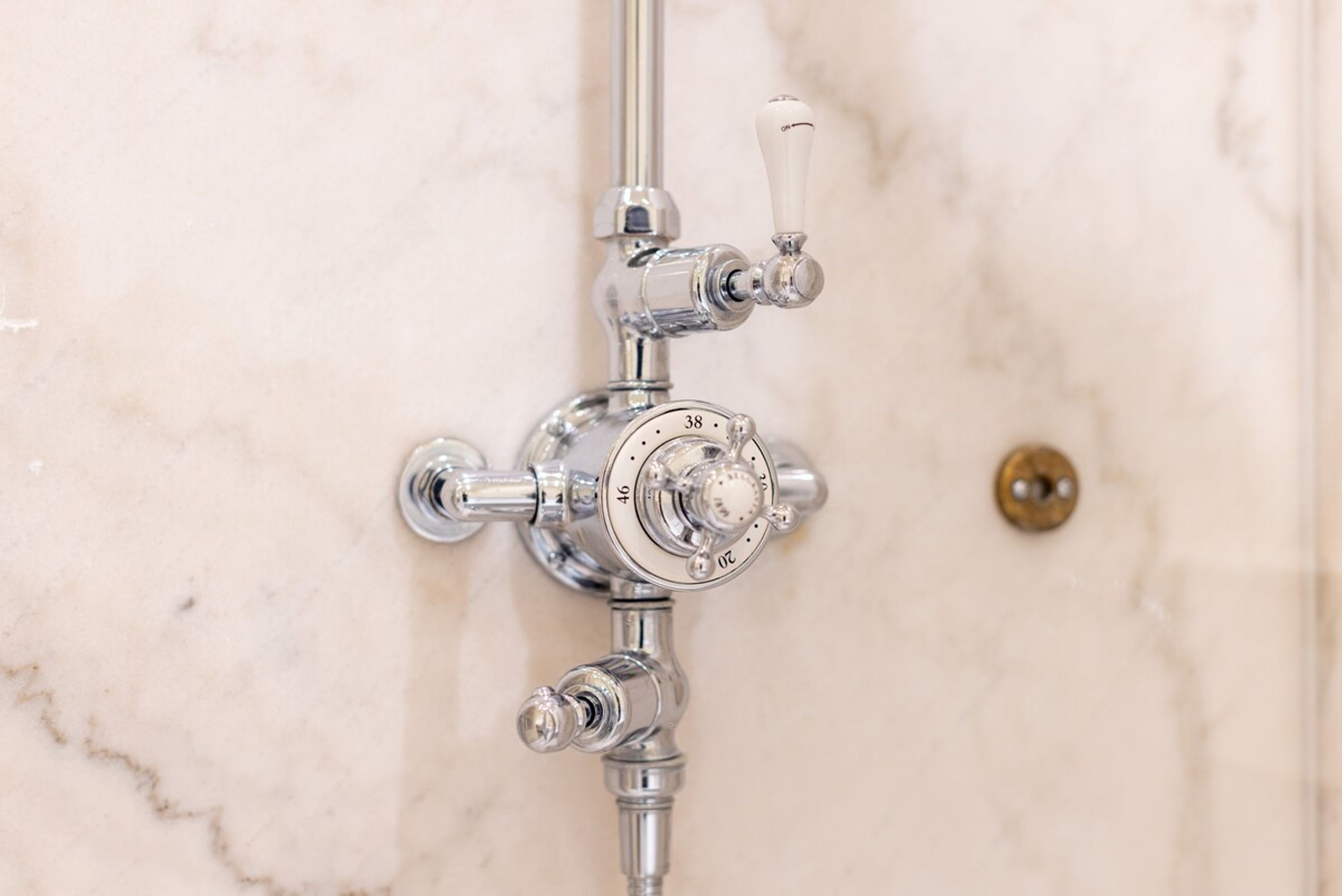 A bathroom with a shower control panel and a single lever handle.
