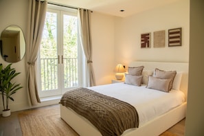 Une chambre à coucher avec un lit, des rideaux, une lampe de chevet, un miroir et une plante en pot.