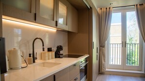 A modern kitchen with a double sink, a kettle, a coffee maker, and a built-in oven. - The Pembridge 11 (London)