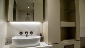 A modern bathroom with a large white sink, a mirror, and a shower area. - The Pembridge 11 (London)
