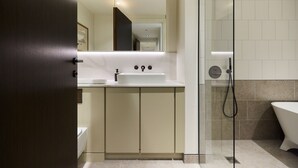 Ein modernes Badezimmer mit Duschkabine aus Glas, einem weißen Waschbecken mit Spiegel darüber und einer Badewanne.