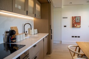 A modern kitchen with a built-in stove, coffee maker, and storage containers. - The Pembridge 12 (London)