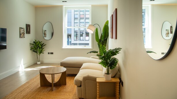 A modern living room with a sofa, coffee table, potted plants, and a large window. - Pembridge Residences - Flat 3 (London)