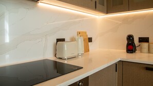 A kitchen with a marble countertop, a toaster, a coffee maker, and a tablet. - Pembridge Residences - Flat 3 (London)