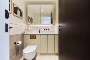 Ein modernes Badezimmer mit Toilette, Waschbecken und Spiegel.