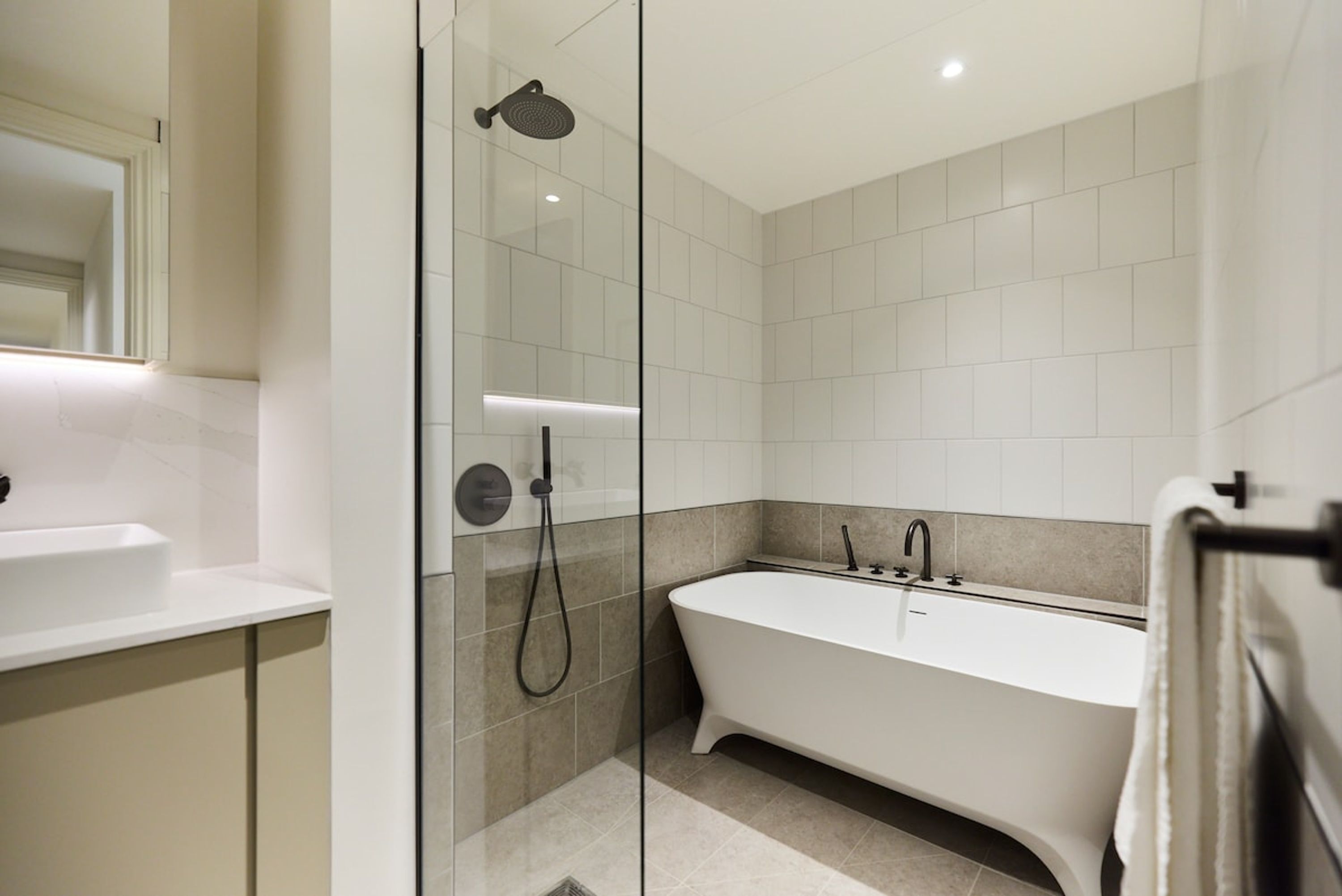 A modern bathroom with a glass-enclosed shower, a freestanding bathtub, and a white sink.