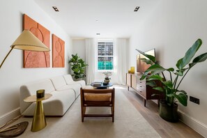 A modern living room with a sofa, coffee table, lamp, and potted plants. - The Pembridge Residences Modern Notting Hill 9b (London)