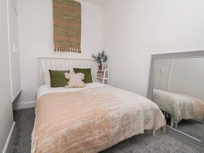 A bedroom with a bed, a mirror, a plant, and a wall-mounted tapestry. - 50 Gladstone Avenue (Chester)