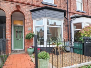 A brick house with a green door, a bay window, and a small garden area with potted plants. - 50 Gladstone Avenue (Chester)