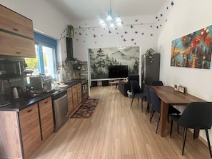 A modern kitchen with a dining area, a TV, and a painting on the wall. - Athens Garden Escape Villa (Athina)