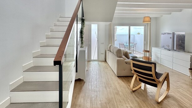 A modern interior with a staircase, a seating area, and a view through a large window. - Casahost Dolce Vita Villa Eira (Costa Teguise)