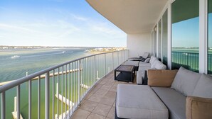 A balcony with a view of the sea, a sofa, and a small table. - Caribe Resort 504D by Liquid Life (Orange Beach)