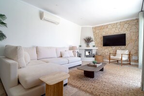 Ein modernes Wohnzimmer mit einer Couch, einem Couchtisch und einer Steinwand mit einem Flachbildfernseher.