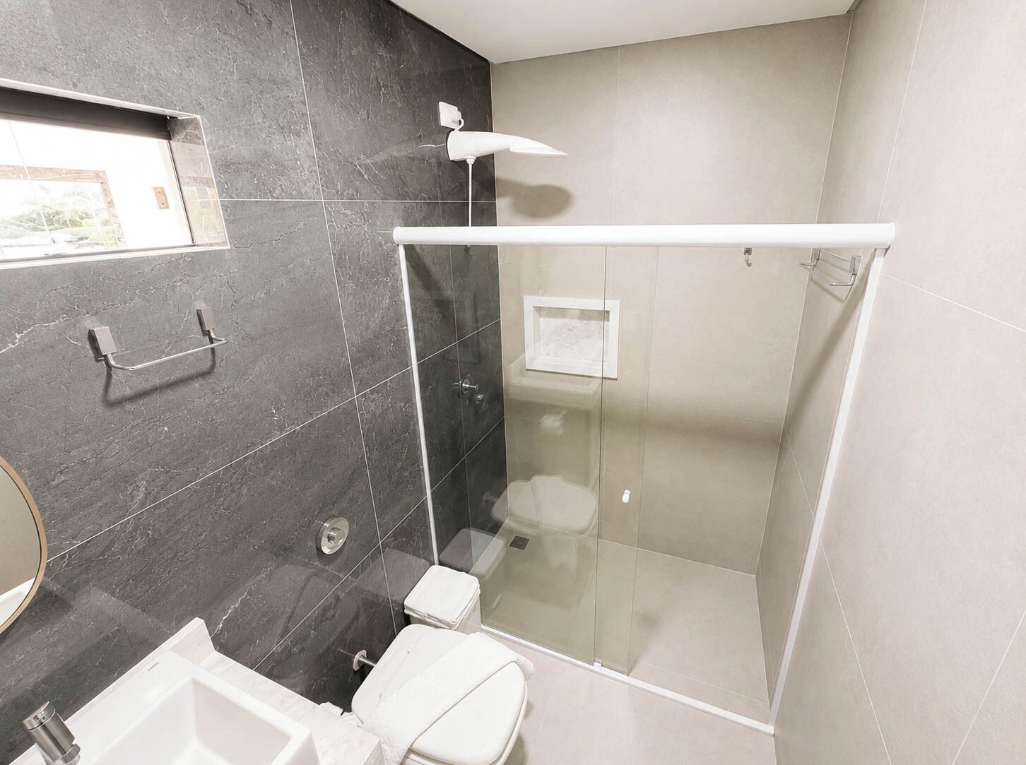 A modern bathroom with a glass-enclosed shower, a toilet, and a sink.
