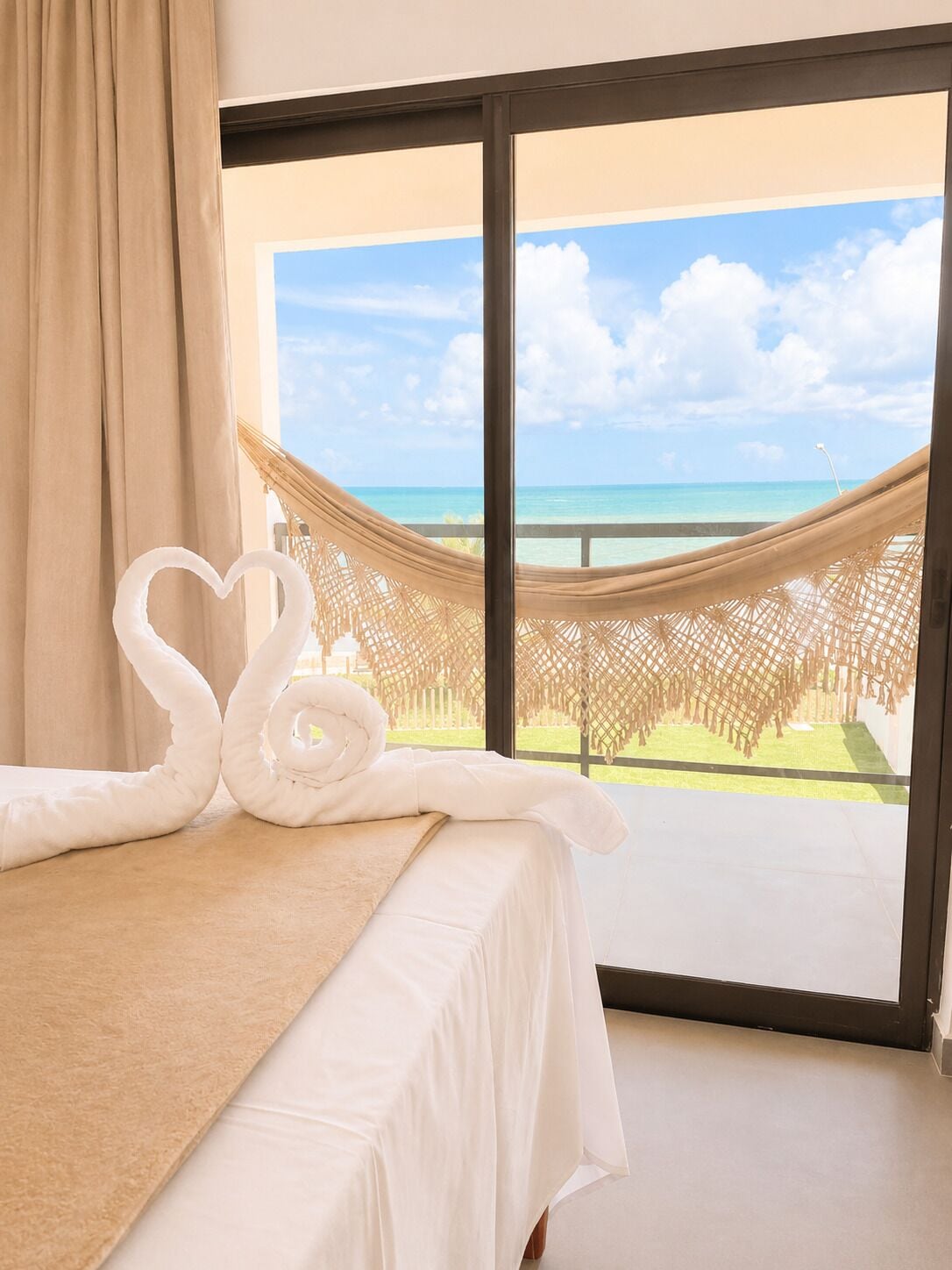 Habitación de hotel con cama, hamaca y vista al océano.
