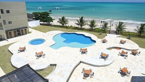 Uma área de piscina com vários espaços de estar e vista para a praia e o oceano.