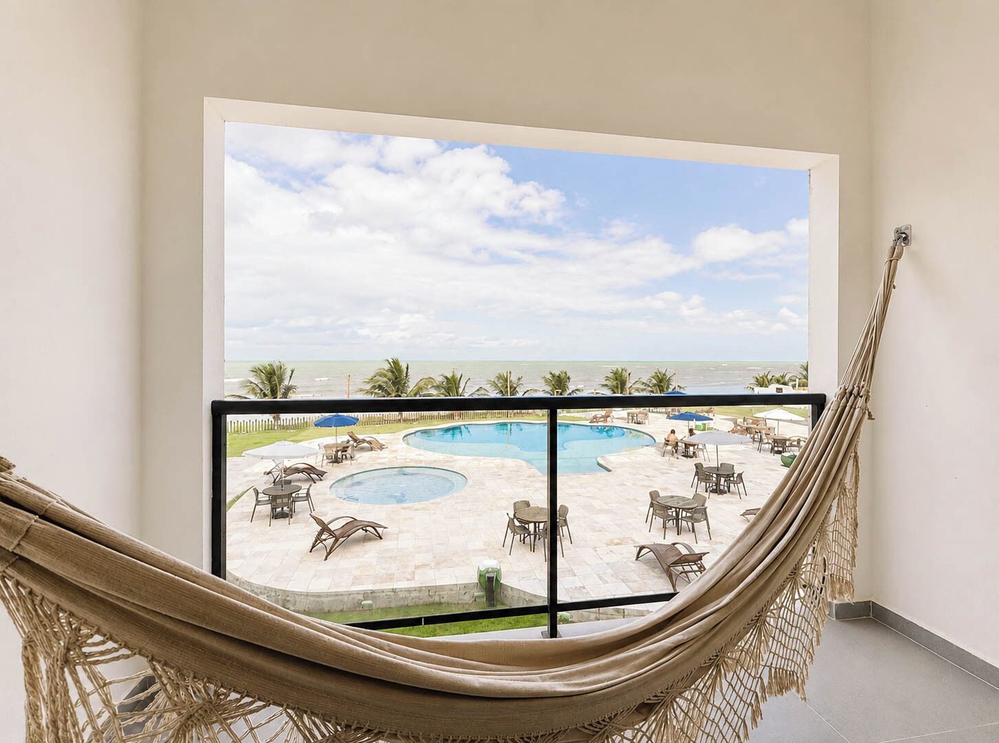 Una hamaca en una habitación con vista a una piscina y una playa.